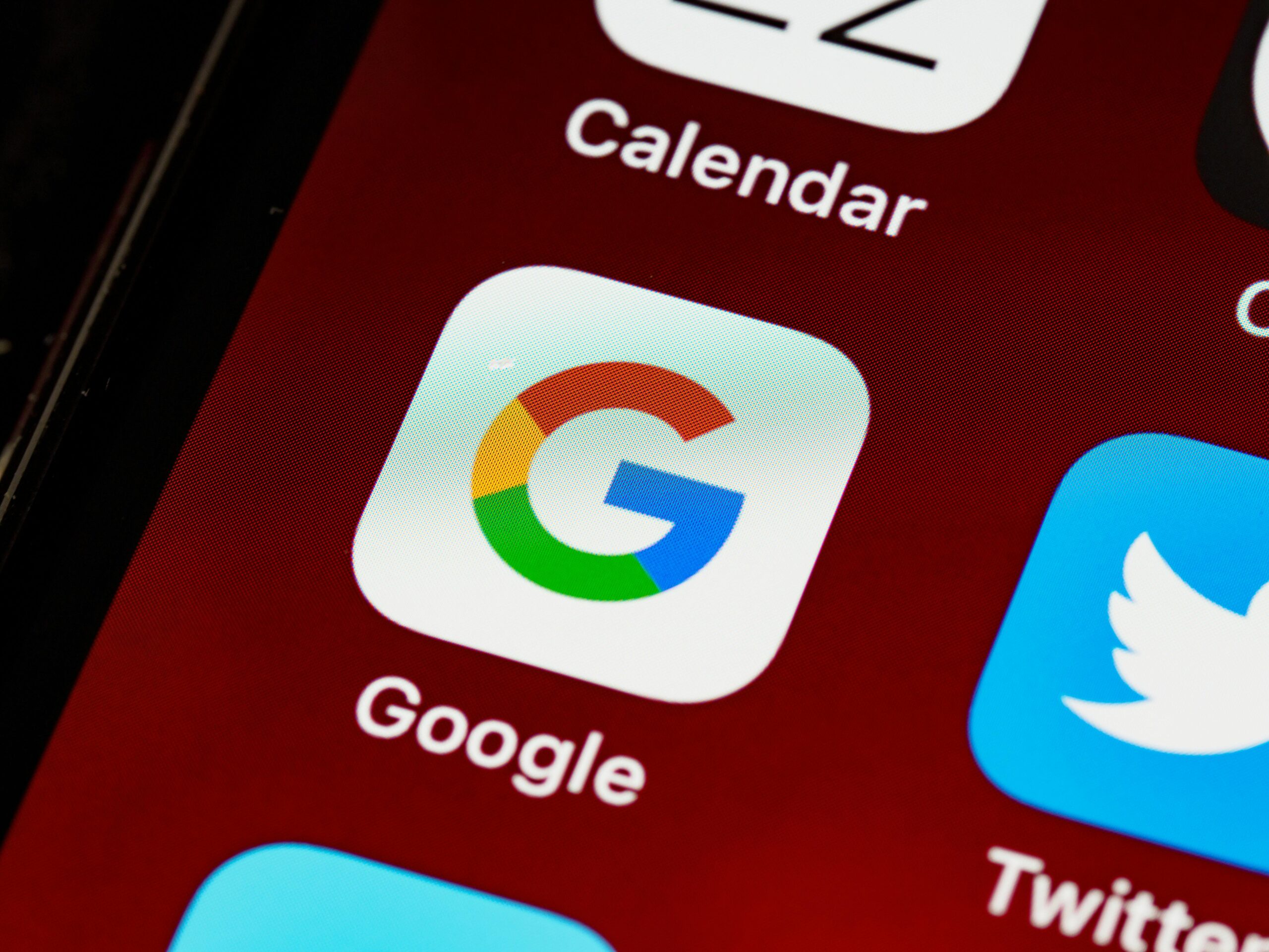 Macro view of a smartphone displaying Google and other app icons on the home screen.